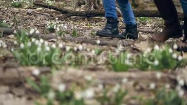 特写镜头，在春天的森林里，在雪地里，穿着靴子走路的女腿，穿着靴子的少年。 一家人散步